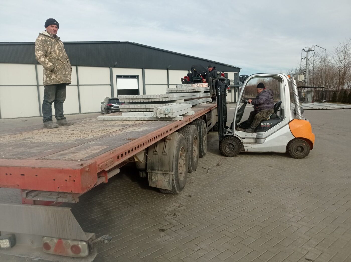 Muncitori și stivuitor încarcă plăci de beton