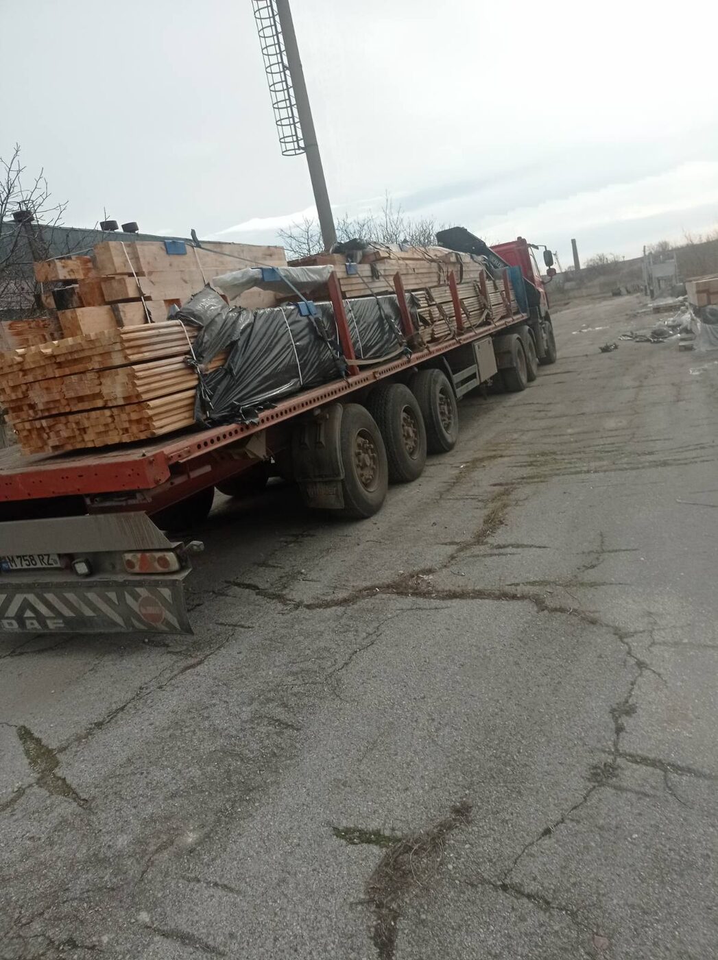Camion cu prelată încărcat cu grinzi și lemn